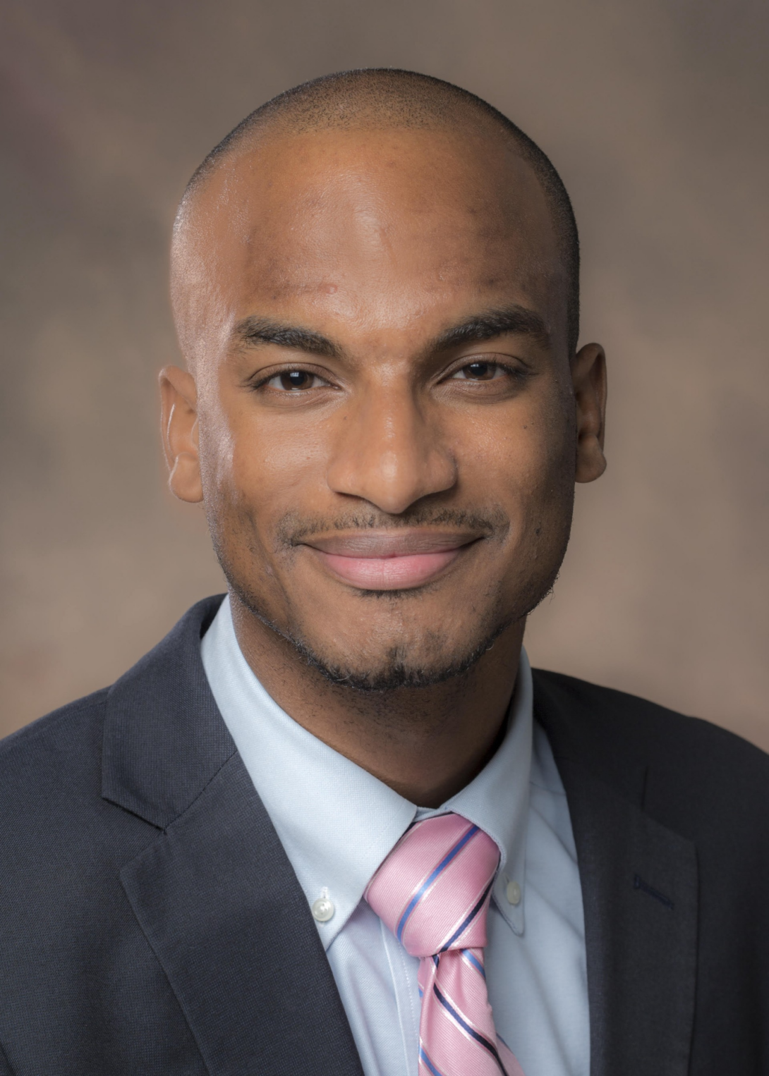 A business headshot of Dr. Gordon Palmer, who is looking directly at the camera. He is wearing a black suit jacket with a blue undershirt.