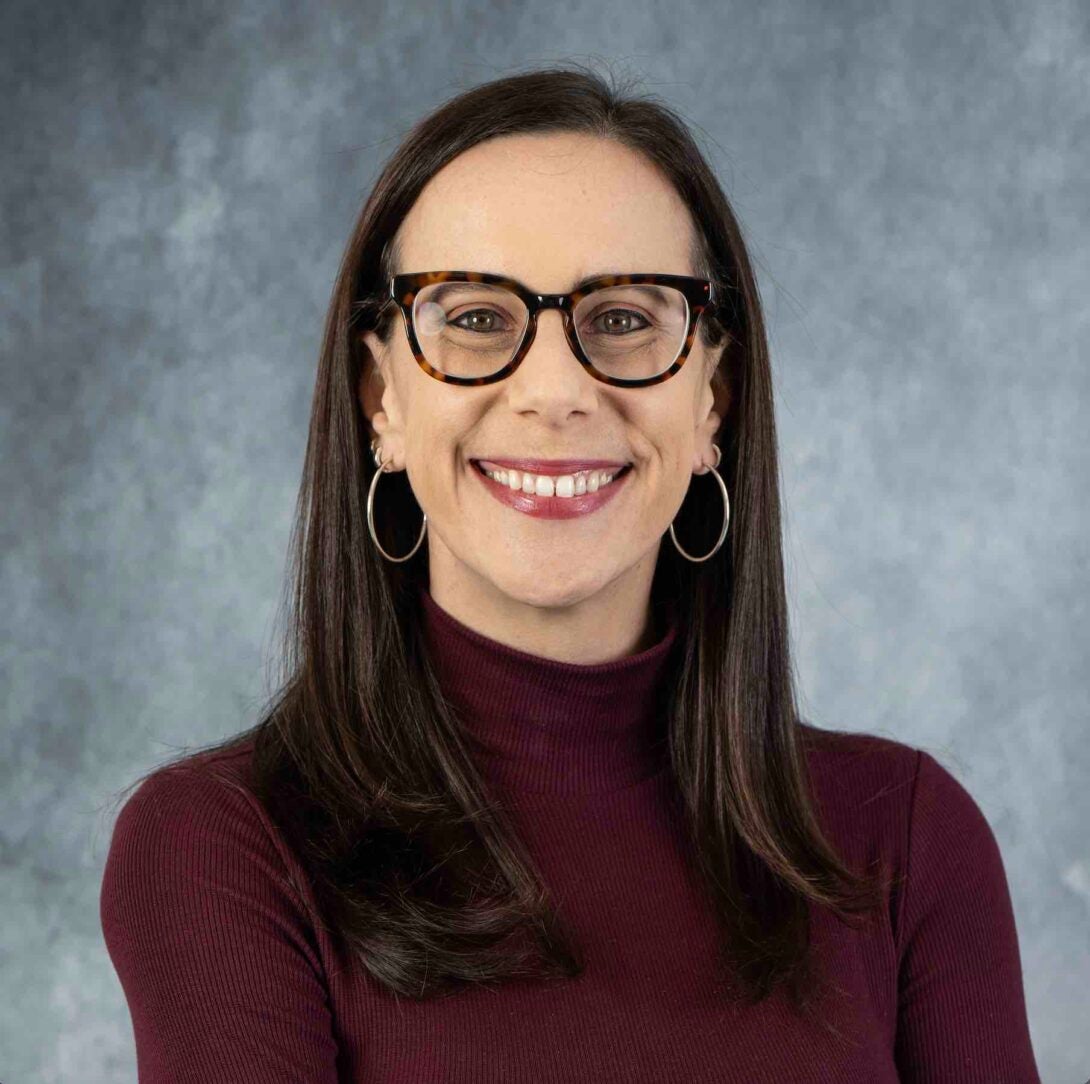 A business headshot of Dr. Jessica Rothstein, who is looking directly at the camera. She is smiling, and wears a brown shirt.